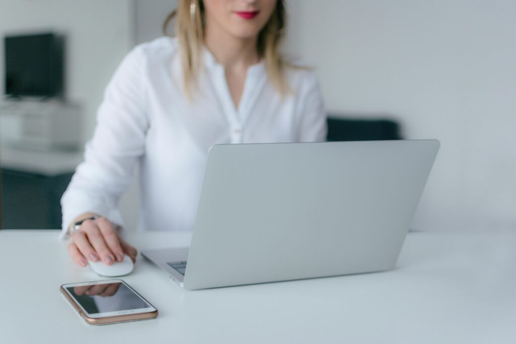 A woman working at a desk using a laptop and smartphone, exemplifying remote work.