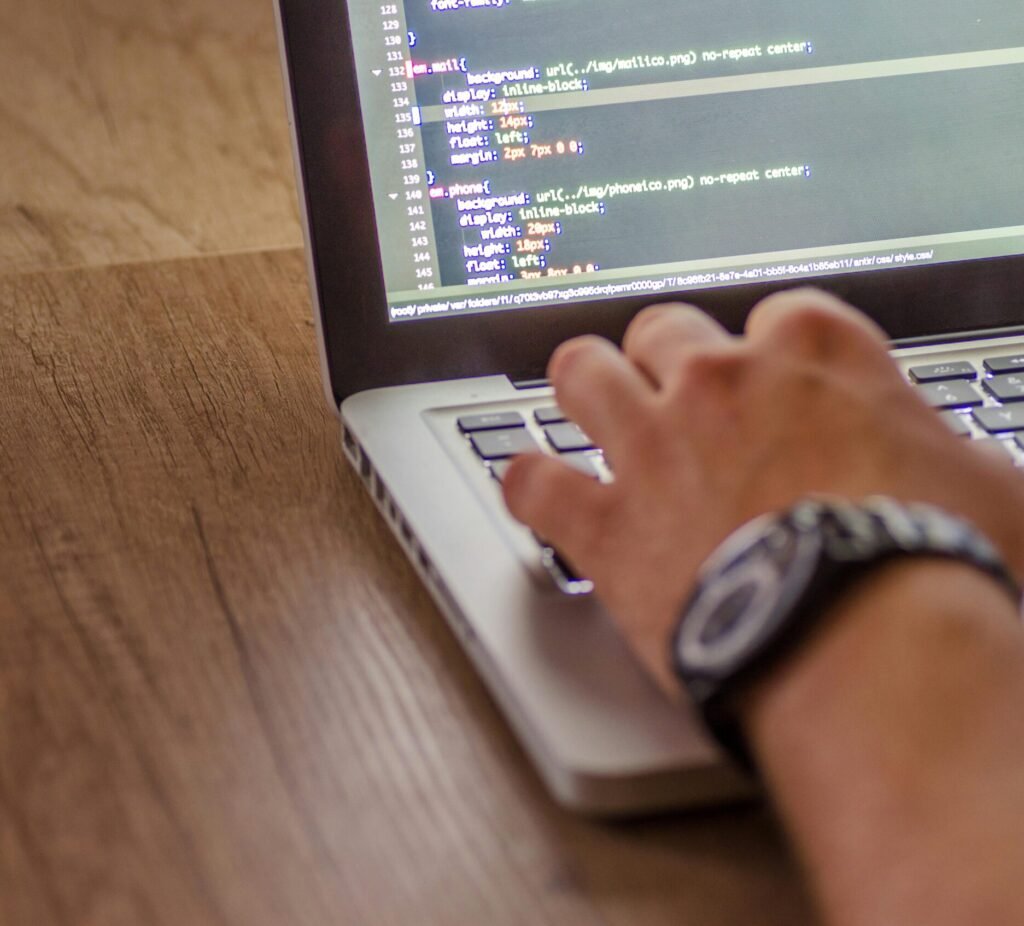 Close-up of a person coding on a laptop, showcasing web development and programming concepts.
